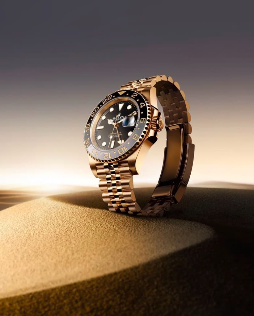 Rose gold luxury wristwatch standing on desert sand under dramatic light